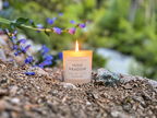 Lit High Meadow spring candle with green stone and blue wildflowers