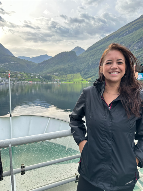 Mountain Senses founder smiling on a boat in Norway, surrounded by green mountains and a calm fjord