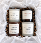 Four Seasons Candle Collection arranged in an open gift box with printed tissue paper and crinkle filler