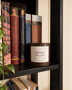 Sienna Valley Ritual Refill candle styled on a bookshelf beside classic books